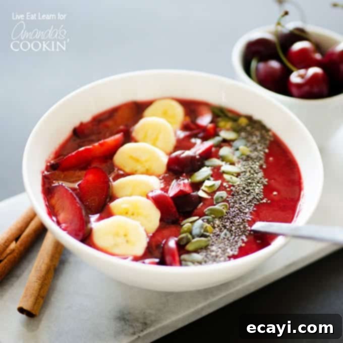 Sun-Kissed Stone Fruit Bowl 3 A close-up shot of a creamy stone fruit smoothie bowl, showcasing the vibrant red color of the plum and cherry base, generously garnished with sliced plums, fresh red cherries, banana rounds, and a healthy mix of nuts and seeds, inviting a delicious spoonful.
