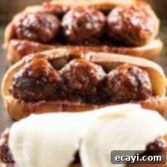 Sweet and Smoky Slow Cooker Meatball Sub Heroes 6 A close up photo of three slow cooker BBQ meatball subs, one topped with provolone cheese.