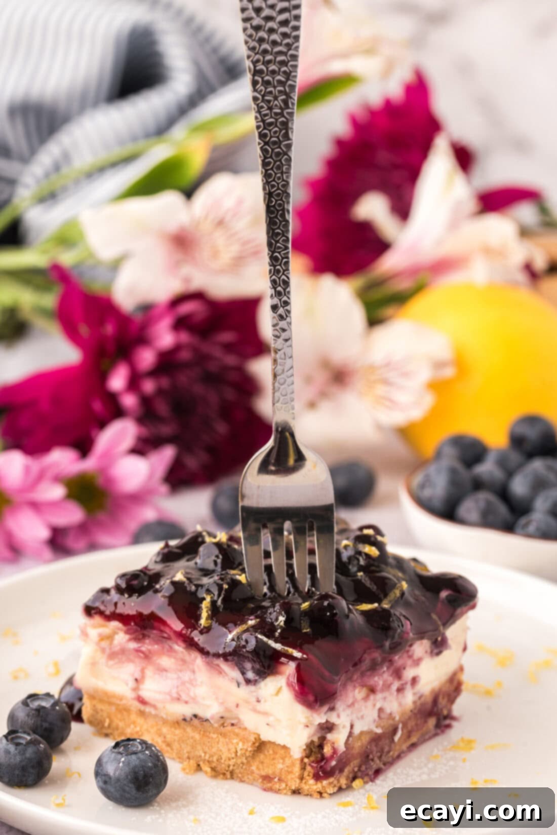 Creamy No-Bake Blueberry Cheesecake 3 Fork pressing into a slice of No Bake Blueberry Cheesecake, revealing the creamy texture.