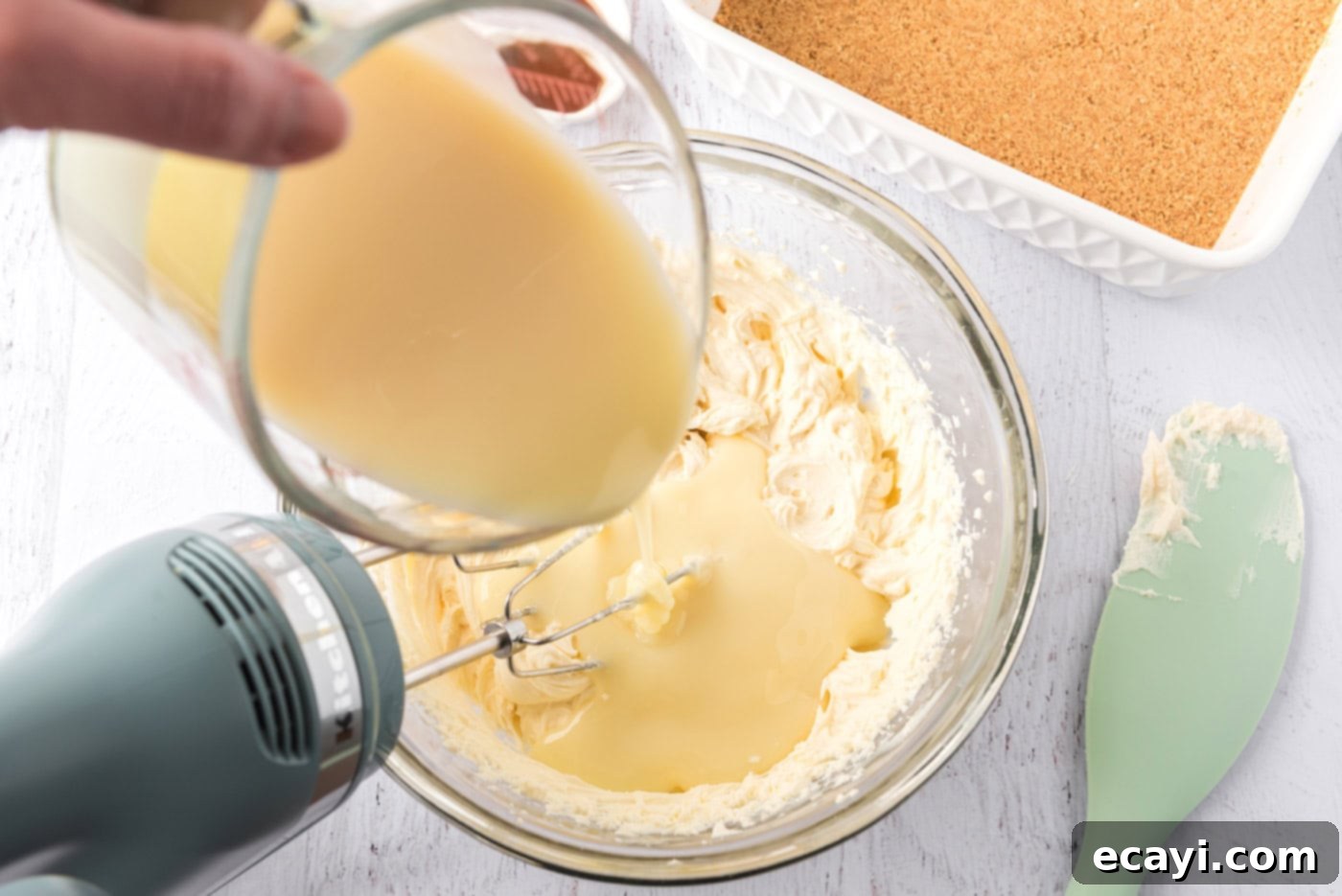Creamy No-Bake Blueberry Cheesecake 7 pouring sweetened condensed milk into mascarpone cheese mixture with a mixer.