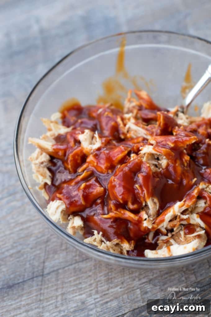 Effortless Slow Cooker BBQ Chicken 3 A clear bowl of shredded chicken with BBQ sauce on top.