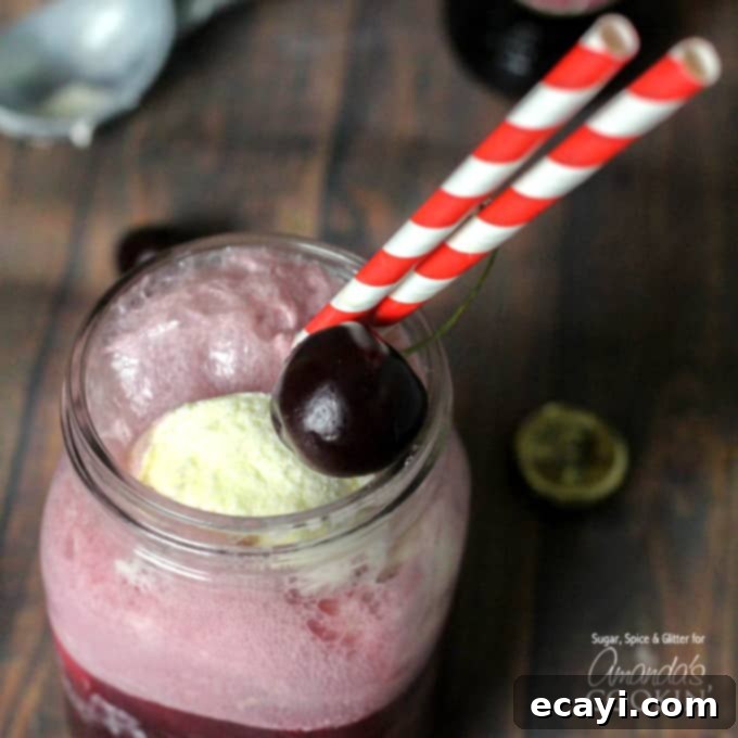 Velvet Cherry Dream 3 A close-up shot of a Black Cherry Float Cocktail in a mason jar, featuring vibrant red and white straws and a plump, fresh cherry for garnish.