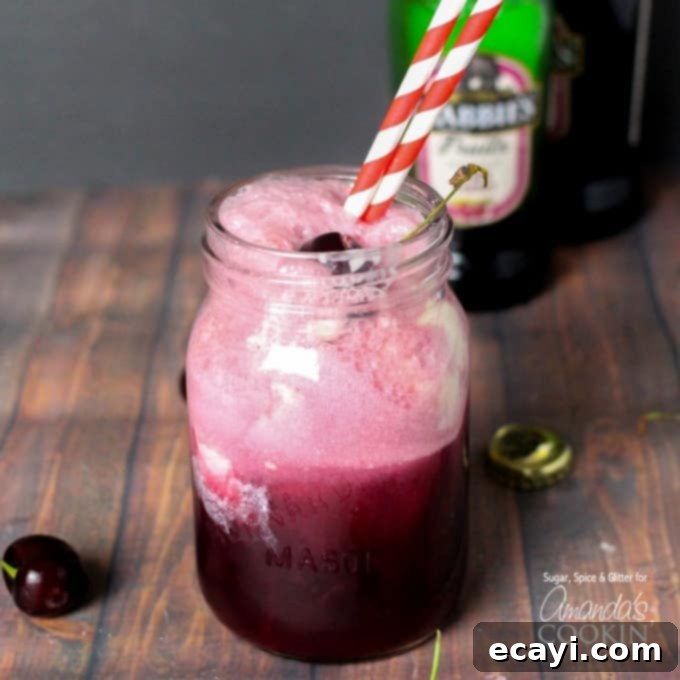 Velvet Cherry Dream 4 An overhead view of a Black Cherry Float Cocktail, served in a rustic mason jar with festive striped straws and a bright red cherry resting on top of the frothy vanilla ice cream.