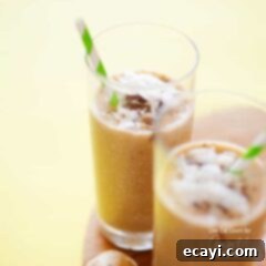 Creamy Coconut Bliss 6 Two tall clear glasses filled with a cozy coconut smoothie and served with a green and white striped straw.