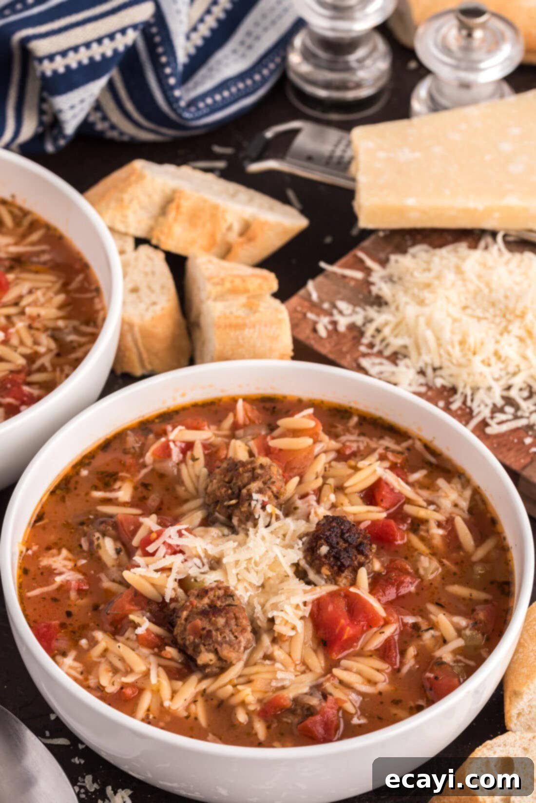 Hearty Sausage Orzo Soup 2 Two bowls of Italian Sausage Tomato Orzo Soup with bread and cheese in the background