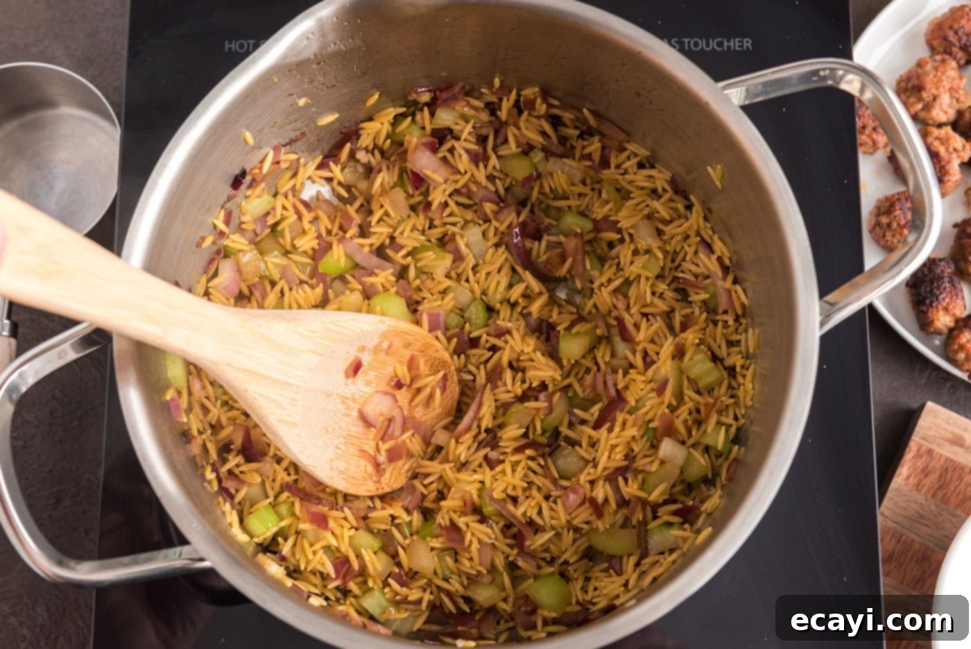 Hearty Sausage Orzo Soup 7 wooden spoon in a pot with orzo, sausage, and veggies