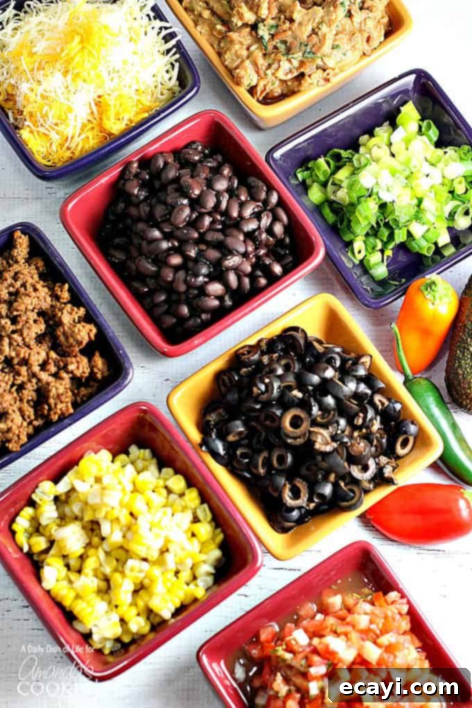 Ultimate Nacho Feast 4 A variety of square bowls filled with taco meat, corn, black beans, black olives, green onions and cheese.
