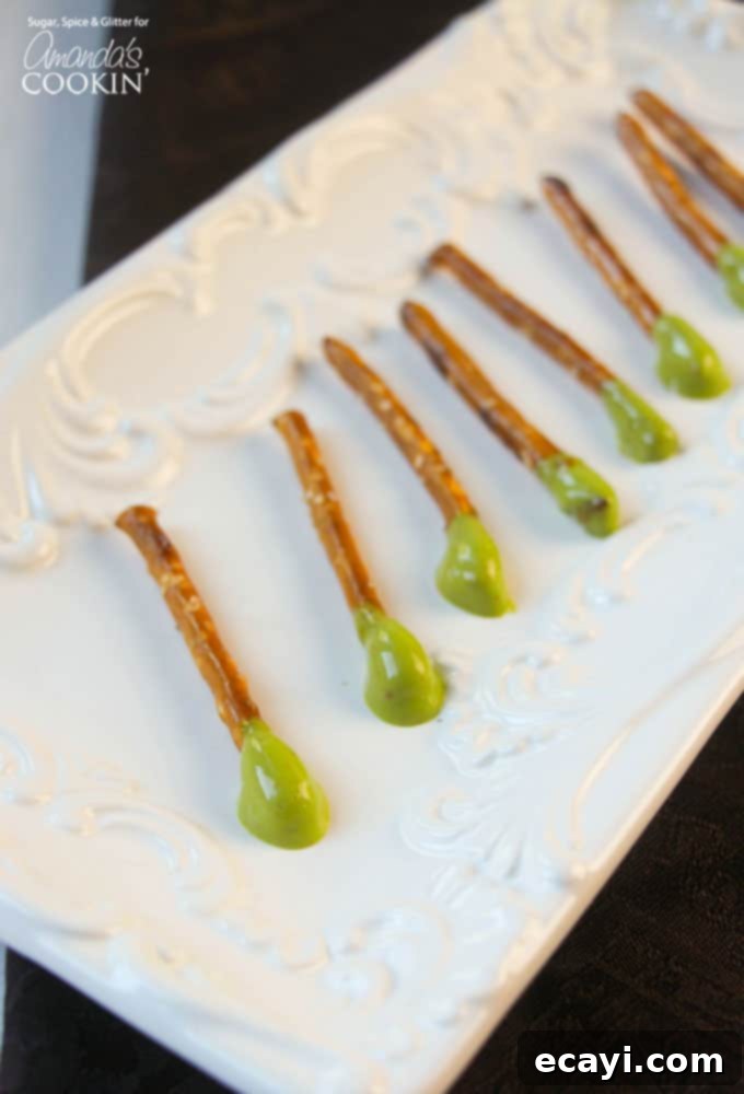 Picky Pops 2 Pretzel sticks with green cheese whiz dipped on one end, arranged on a rustic wooden surface for a Halloween party snack.
