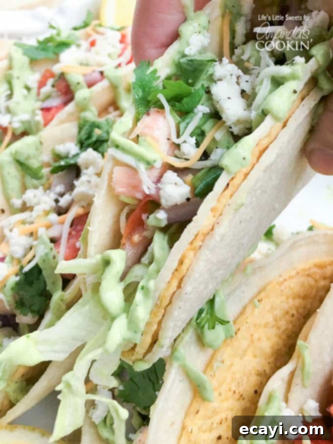 Zesty Salmon Street Tacos 9 A close-up, mouthwatering photo of a single salmon taco, beautifully loaded with flaky salmon, fresh salsa, and creamy avocado sauce, ready to be eaten.