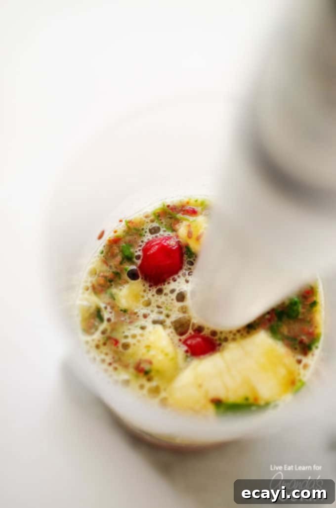 Holiday Reset: Cranberry Cleanse Smoothie 4 A close up photo of a cranberry smoothie being blended with an immersion blender.
