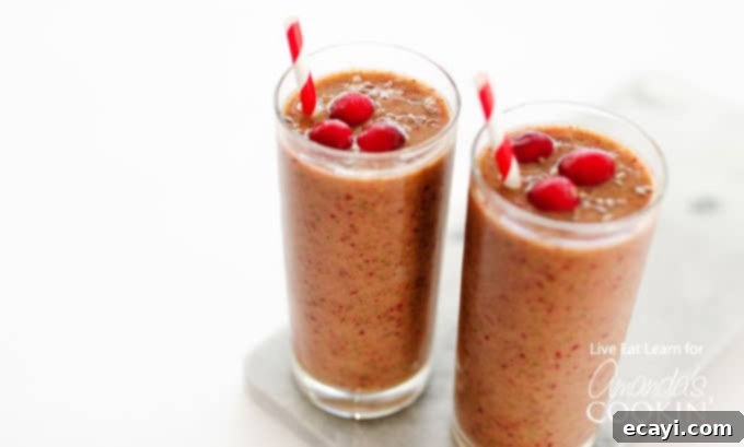 Holiday Reset: Cranberry Cleanse Smoothie 6 A close up of two cranberry smoothies with cranberries on top and served with a straw.