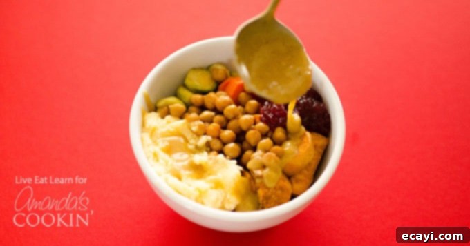 Ultimate Thanksgiving Leftovers Bowl 4 A beautifully presented Thanksgiving leftovers bowl, highlighting the vibrant colors and diverse textures of its components: golden roasted chickpeas and vegetables, creamy mashed potatoes, and rich gravy.