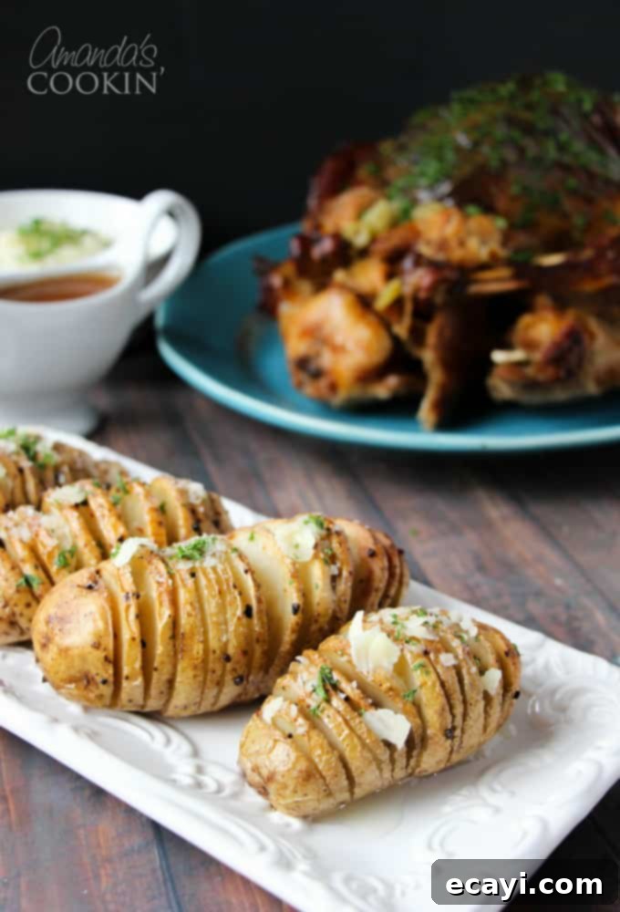 Golden Fan-Cut Potatoes 2 Golden brown Hasselback potatoes resting on a rectangular white plate, garnished with fresh herbs, ready to be served.