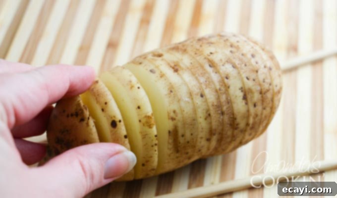 Golden Fan-Cut Potatoes 7 Hasselback potatoes step 1: Raw russet potatoes prepared for slicing, with two chopsticks positioned on either side to guide the cuts.