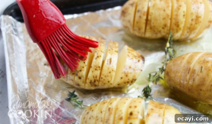 Golden Fan-Cut Potatoes 8 Hasselback potatoes step 2: Sliced russet potatoes lined up on a baking sheet, showing the deep, fanned-out cuts achieved with the chopstick method.