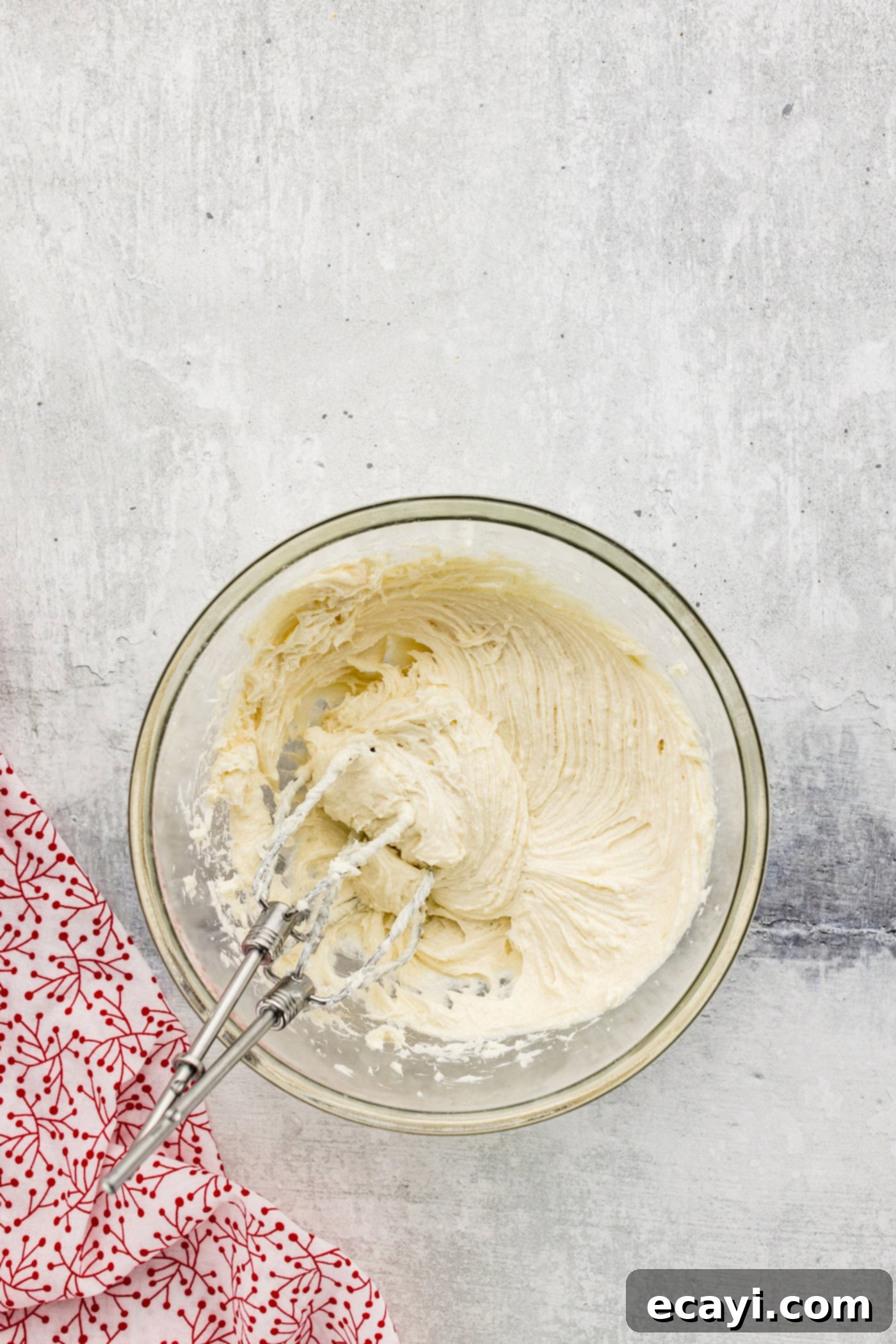 Peppermint Swirl Danish 5 Cream cheese, sugar, and vanilla being thoroughly beaten with a hand mixer in a bowl until smooth and creamy, forming the delicious danish filling