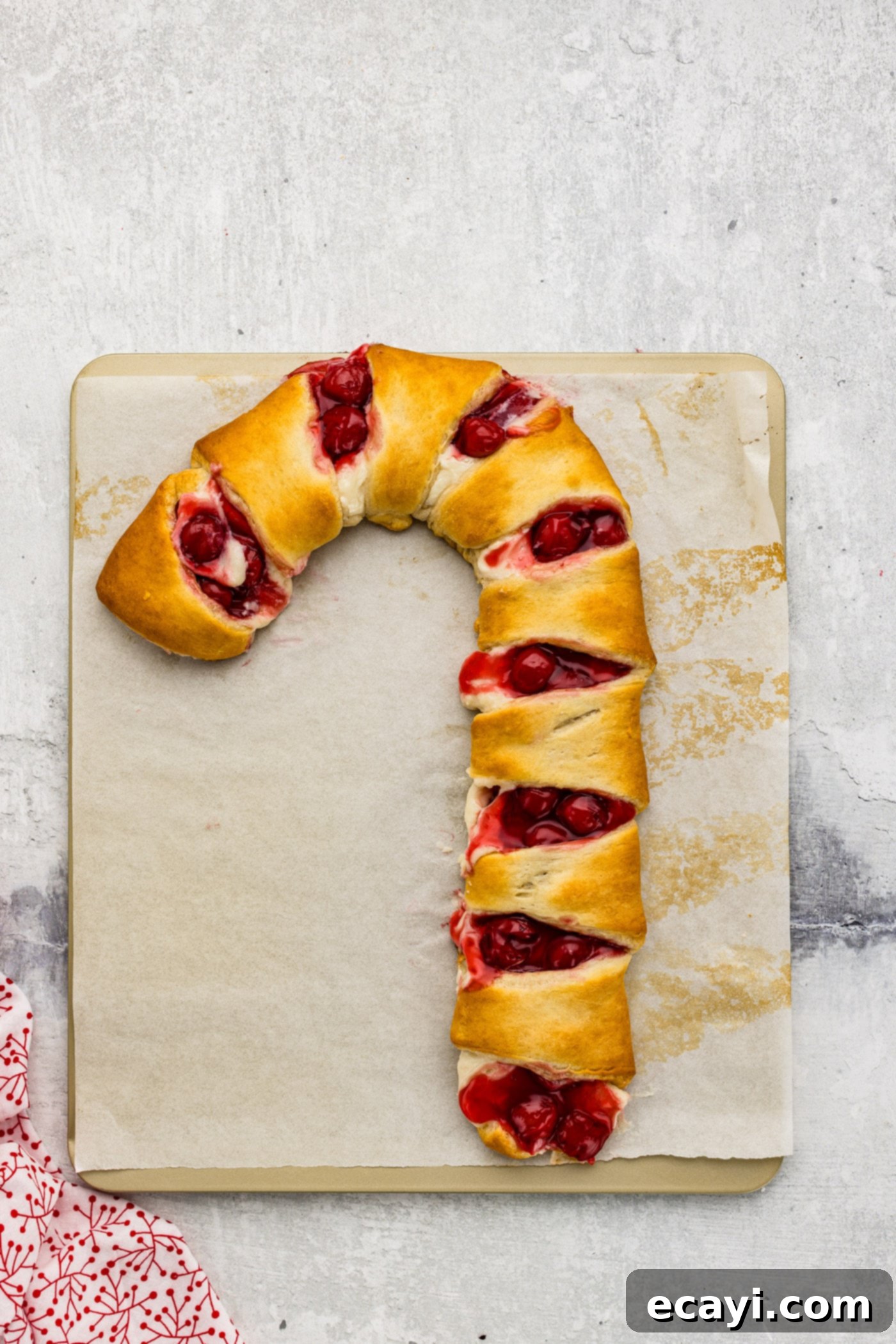 Peppermint Swirl Danish 10 Two freshly baked candy cane danishes, golden brown and perfectly puffed, cooling on parchment-lined cookie sheets after baking, awaiting their glaze