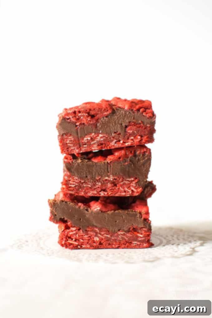 Red Velvet Oatmeal Fudge Obsession 2 Three squares of red velvet oatmeal fudge bars stacked on top of each other, showcasing the beautiful red cookie and dark fudge layers.