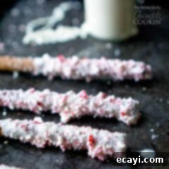 Holiday Minty Pretzel Crunch 5 A close up photo of three white chocolate candy cane pretzel sticks.