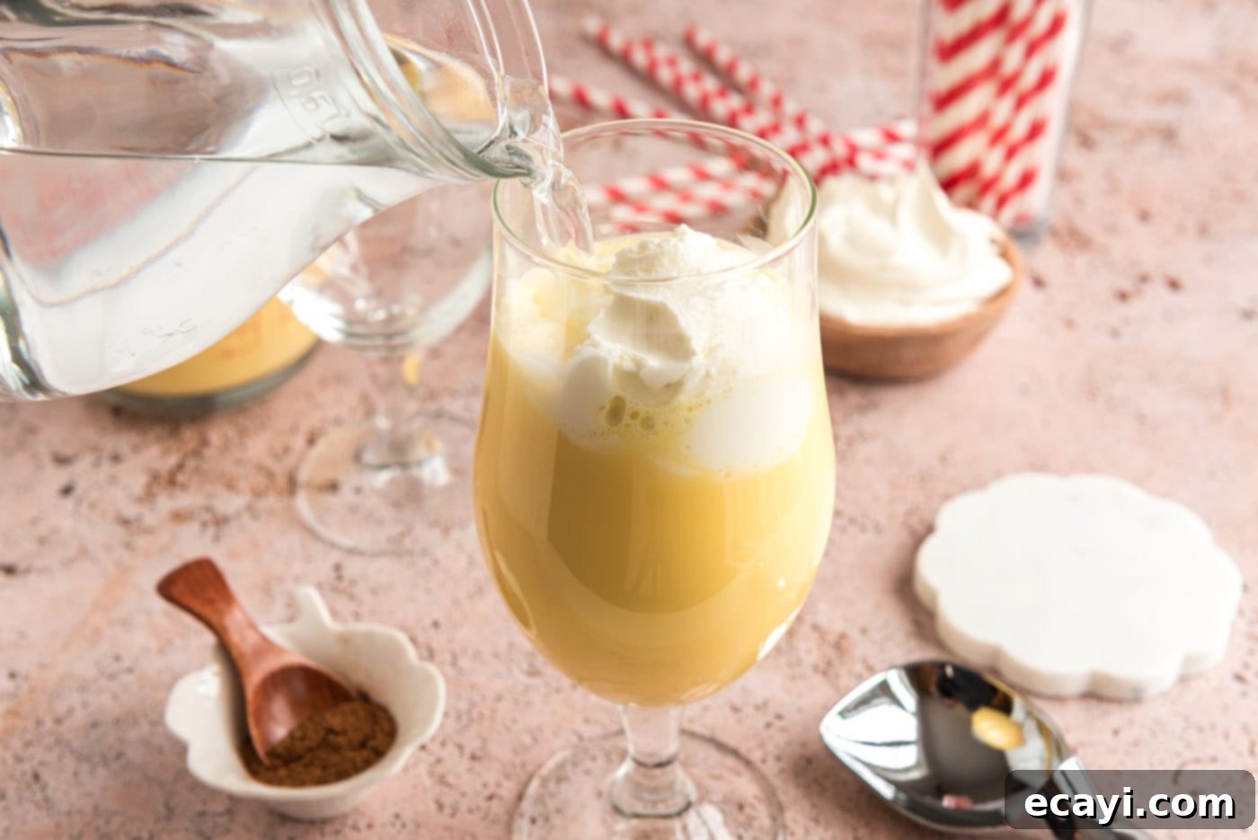 Creamy Eggnog Delight 7 Carefully pouring sparkling club soda into a glass containing eggnog and vanilla ice cream