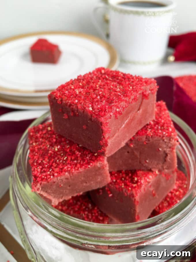 Decadent Red Velvet Fudge 2 Vibrant red velvet fudge squares topped with festive red sprinkles, arranged artfully on a white plate, ready to be enjoyed.