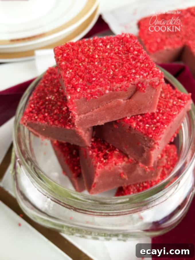 Decadent Red Velvet Fudge 5 A close-up view of perfectly cut red velvet fudge squares, revealing their smooth texture and rich color, adorned with sprinkles.
