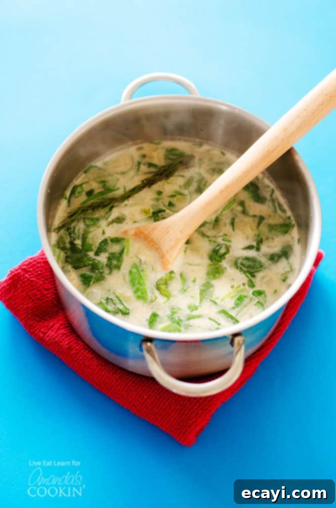 Effortless White Bean Soup 2 A pot of creamy white bean soup with a wooden spoon resting inside it, ready to be served.