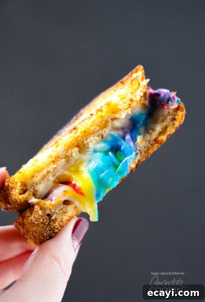 Who says you shouldn't play with your food? Make some fun food this St. Patrick's Day with this rainbow grilled cheese! Perfect for unicorn lovers too! #unicorn #rainbow #cutefood #cheese #stpatricksday #spring #sandwich Rainbow Grilled Cheese sandwich with colorful cheese inside, perfect for St. Patrick's Day or unicorn themes.