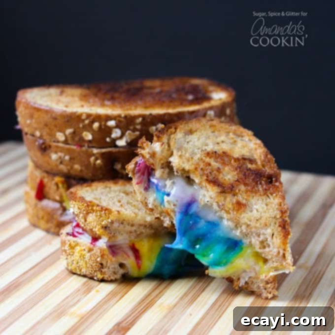 Who says you shouldn't play with your food? Make some fun food this St. Patrick's Day with this rainbow grilled cheese! Perfect for unicorn lovers too! #unicorn #rainbow #cutefood #cheese #stpatricksday #spring #sandwich Close-up of a Rainbow Grilled Cheese Sandwich revealing multicolored melted cheese inside, ready to be enjoyed.