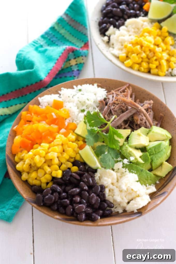 Naked Burrito 2 An overhead of a brown bowl filled with white rice, bell pepper, corn, black beans, crumbled queso fresco, avocado, lime and cooked beef.