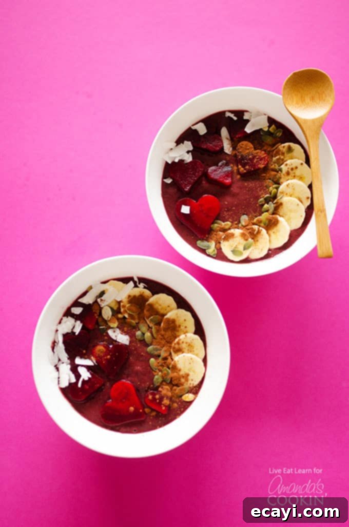 Decadent Red Velvet Smoothie Bowls 3 Two white bowls filled with red velvet smoothie and a wooden spoon.