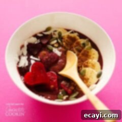 Decadent Red Velvet Smoothie Bowls 5 A white bowl filled with a red velvet smoothie and a wooden spoon.