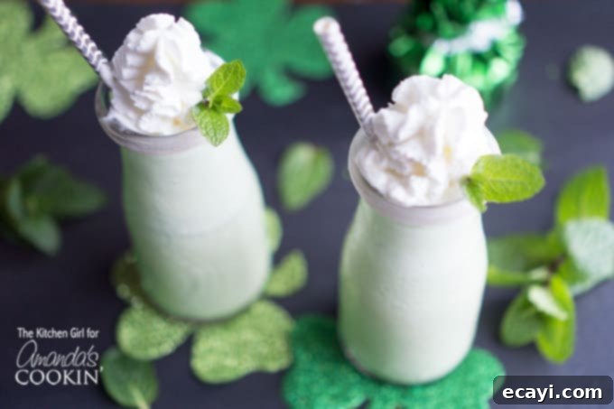 Naturally Green Shamrock Shake - ice cream shake made with fresh mint. Great way to avoid food dyes while celebrating the Irish holiday. #shamrockshake #greensmoothie #smoothierecipes #milkshake #mint #dessert #stpatricksday #milkshakerecipes Two glasses of naturally green shamrock shakes, garnished with fresh mint leaves and whipped cream, ready for St. Patrick's Day celebration.