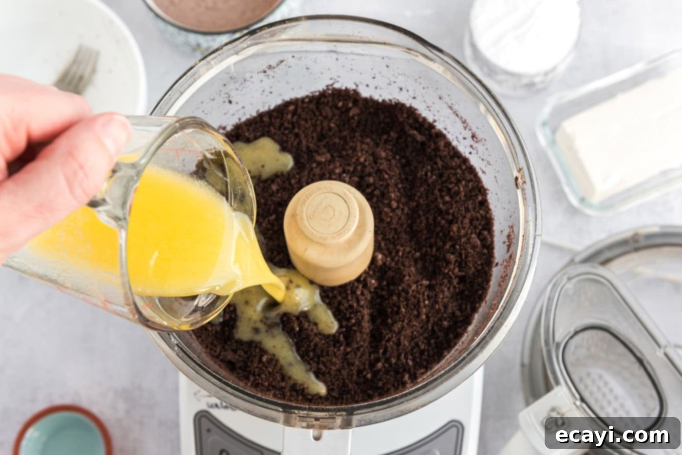 No-Bake Mint Chocolate Lasagna 5 pouring melted butter over Oreo cookie crumbs in a food processor