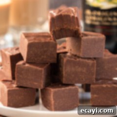 Effortless 4 Ingredient Baileys Fudge 11 Close up photo of a stack of fudge squares with a bite taken out of the top square, highlighting the rich Bailey's flavor