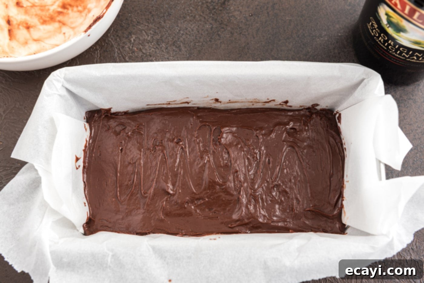Effortless 4 Ingredient Baileys Fudge 8 Smooth chocolate fudge mixture being spread into a parchment-lined loaf pan