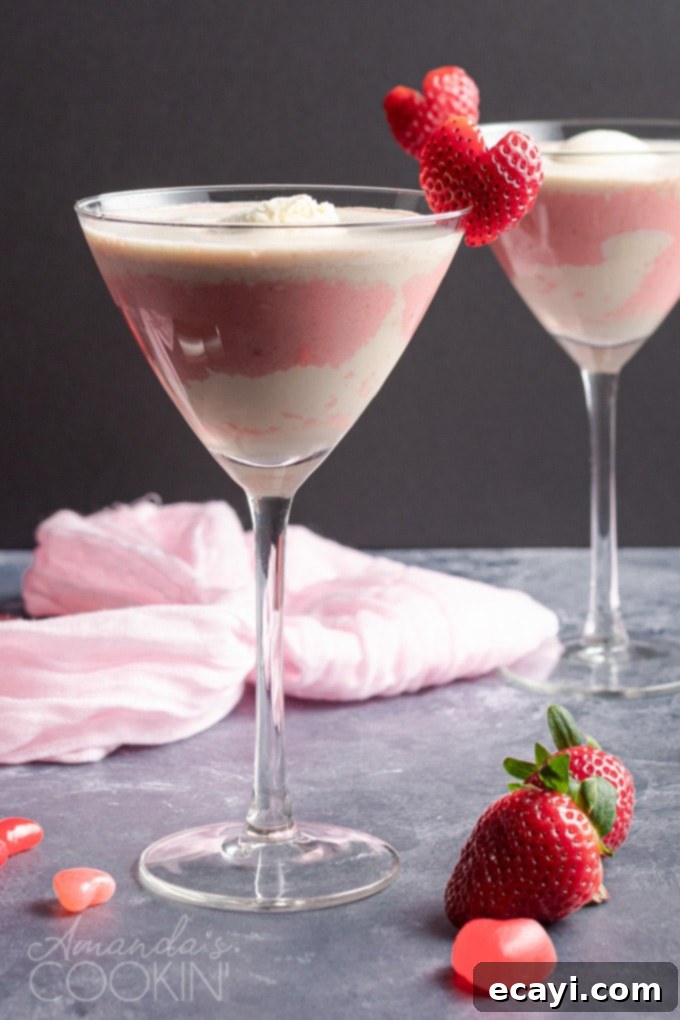 This Valentine's Mudslide adds fresh strawberries into the mix for a fresh and fruity take on a frozen cocktail classic. Make this for someone you love! #cocktails #valentinesday #mudslide #mudslidecocktail #partydrinks #strawberry #icecream #baileys #kahlua Pink Mudslide cocktail in a martini glass garnished with a fresh strawberry