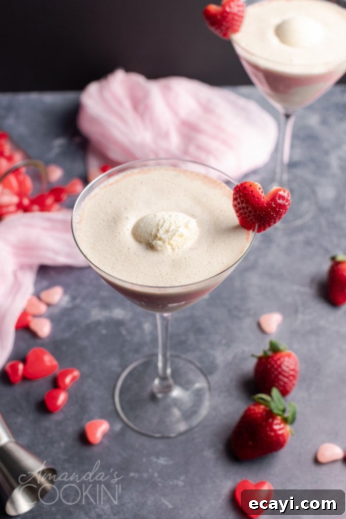 This Valentine's Mudslide adds fresh strawberries into the mix for a fresh and fruity take on a frozen cocktail classic. Make this for someone you love! #cocktails #valentinesday #mudslide #mudslidecocktail #partydrinks #strawberry #icecream #baileys #kahlua Close-up of vanilla ice cream scoop swirling into a Pink Mudslide drink