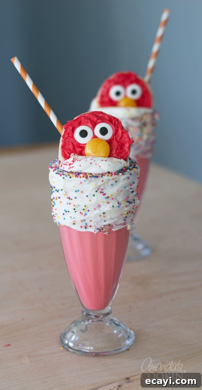 Ultimate Cookie Monster Freakshakes 6 A vibrant Elmo Freakshake, featuring a bright red milkshake topped with whipped cream, sprinkles, and a cheerful Elmo cookie. The background suggests a festive party setting, showcasing another fun, character-themed extreme milkshake.