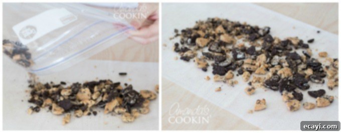 Ultimate Cookie Monster Freakshakes 3 Crushed cookie crumbles spread evenly on a piece of parchment paper, ready for decorating milkshake glasses. The crumbles consist of a mix of chocolate and cream colors from the different cookies, forming a textured base.