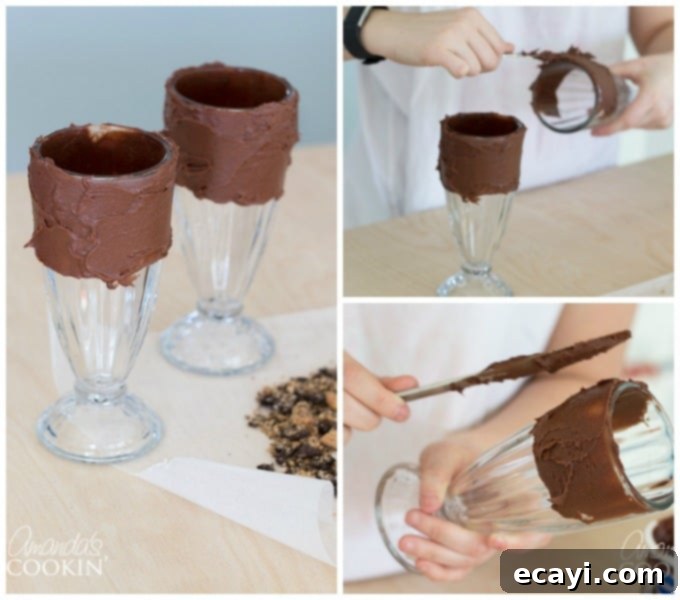 Ultimate Cookie Monster Freakshakes 4 A milkshake glass being coated with chocolate frosting around its rim using a butter knife, demonstrating the preparation step before adding cookie crumbles. The frosting provides a sticky base for the decorations.