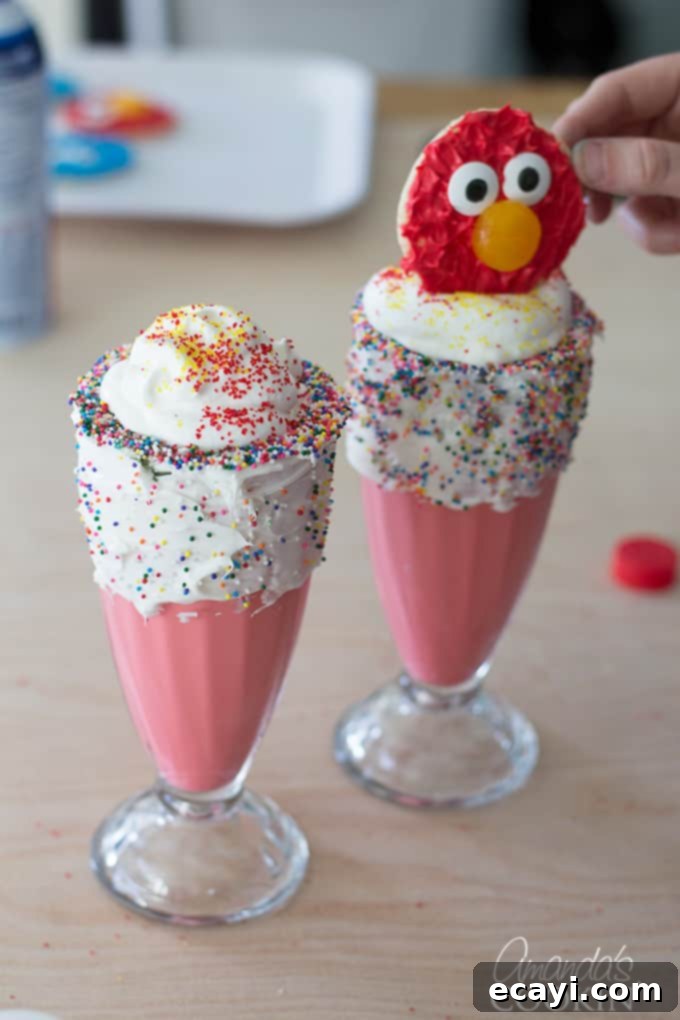 Elmo's Ultimate Freakshakes 7 A perfectly blended Elmo red milkshake being poured into a decorated glass, ready for whipped topping and an Elmo cookie.
