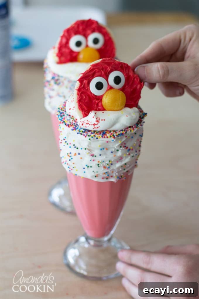 Elmo's Ultimate Freakshakes 8 Two fully assembled Elmo Freakshakes, featuring vibrant red milkshakes, generous whipped topping, and cute Elmo cookies as the final touch.