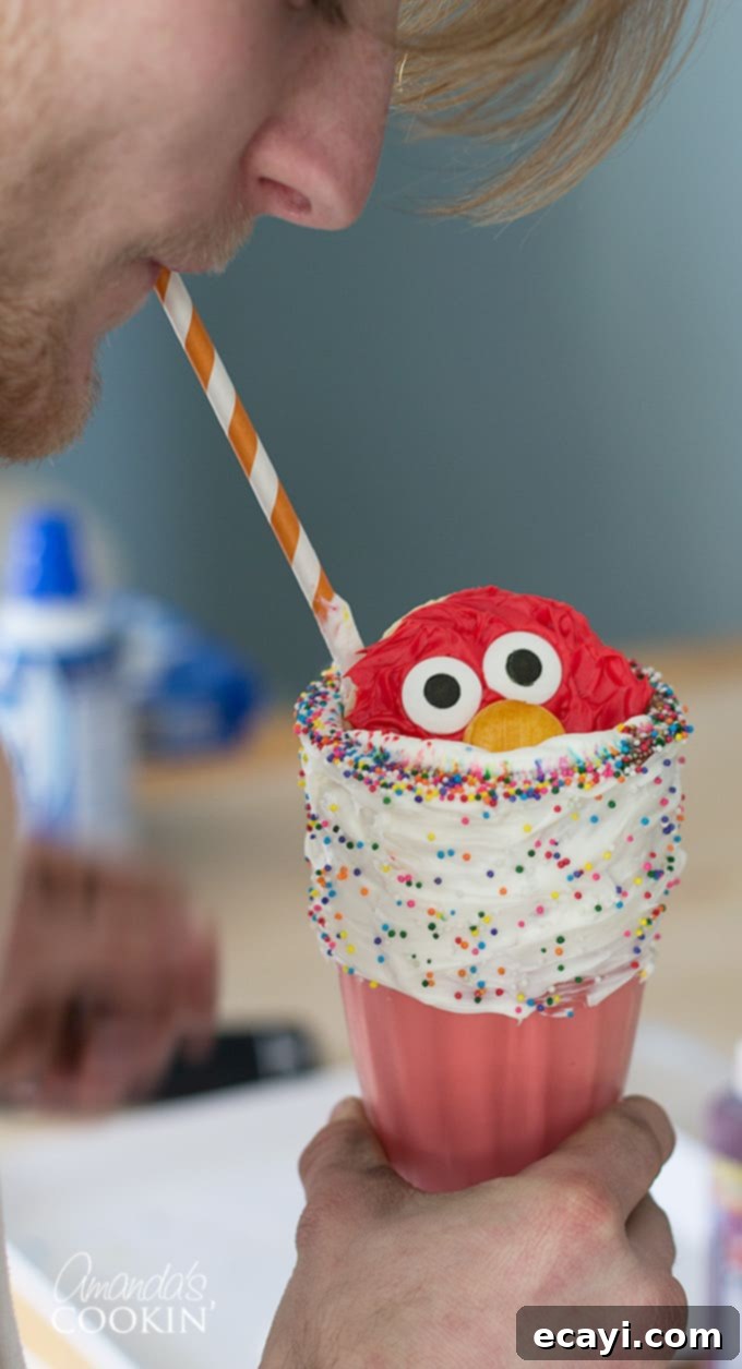 Elmo Freakshakes will put a smile on your kids face! A smiling child happily sips an Elmo Freakshake through a straw, showing the joy these colorful drinks bring.