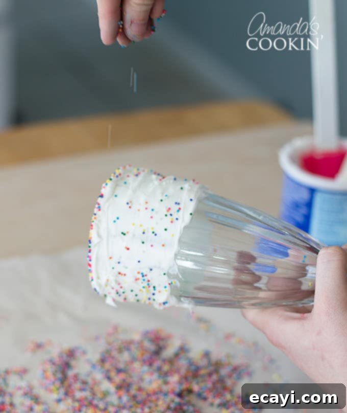 Sprinkling on multi-colored sprinkles- Elmo Freakshakes Generously sprinkling multicolored sprinkles over the vanilla-frosted rim of a milkshake glass for an extra pop of color.