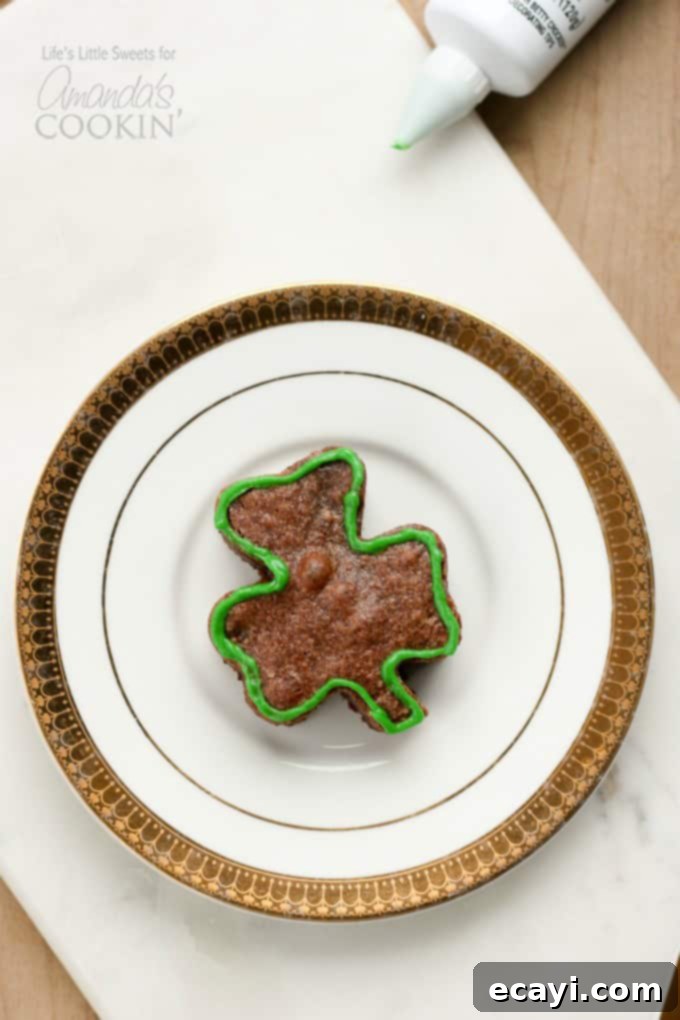 Lucky Clover Brownie Bites 7 A perfectly cut shamrock shaped brownie adorned with a dusting of confectioner's sugar on a plate.
