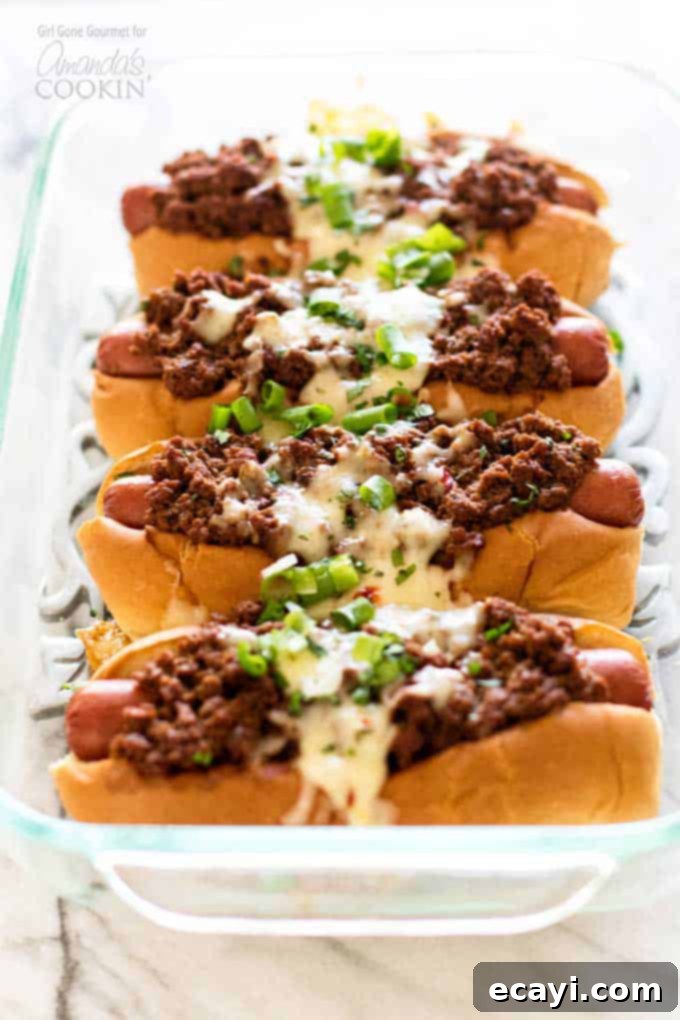 Hot dogs topped with a simple and flavorful chili, pepper jack cheese, and fresh green onions - these oven chili dogs are always a crowd favorite! #chilidog #howtomakechilidogs #chilidogrecipe #chilicheesedogs #chili #hotdog #cheese #oven #baked #weeknightdinner #easydinner #easymeals Hot dogs nestled in soft buns