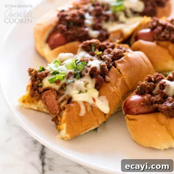 Hot dogs topped with a simple and flavorful chili, pepper jack cheese, and fresh green onions - these oven chili dogs are always a crowd favorite! #chilidog #howtomakechilidogs #chilidogrecipe #chilicheesedogs #chili #hotdog #cheese #oven #baked #weeknightdinner #easydinner #easymeals  chili dog with a bit out of it
