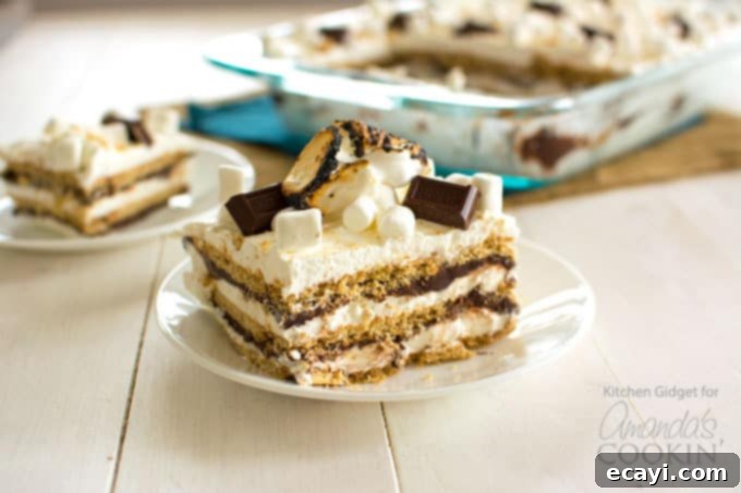 Prepare to impress with this stunning S'mores Icebox Cake, a truly irresistible no-bake dessert. a whole s'mores icebox cake in a glass pan, with a slice already removed, garnished with toasted marshmallows, chocolate, and graham cracker crumbs