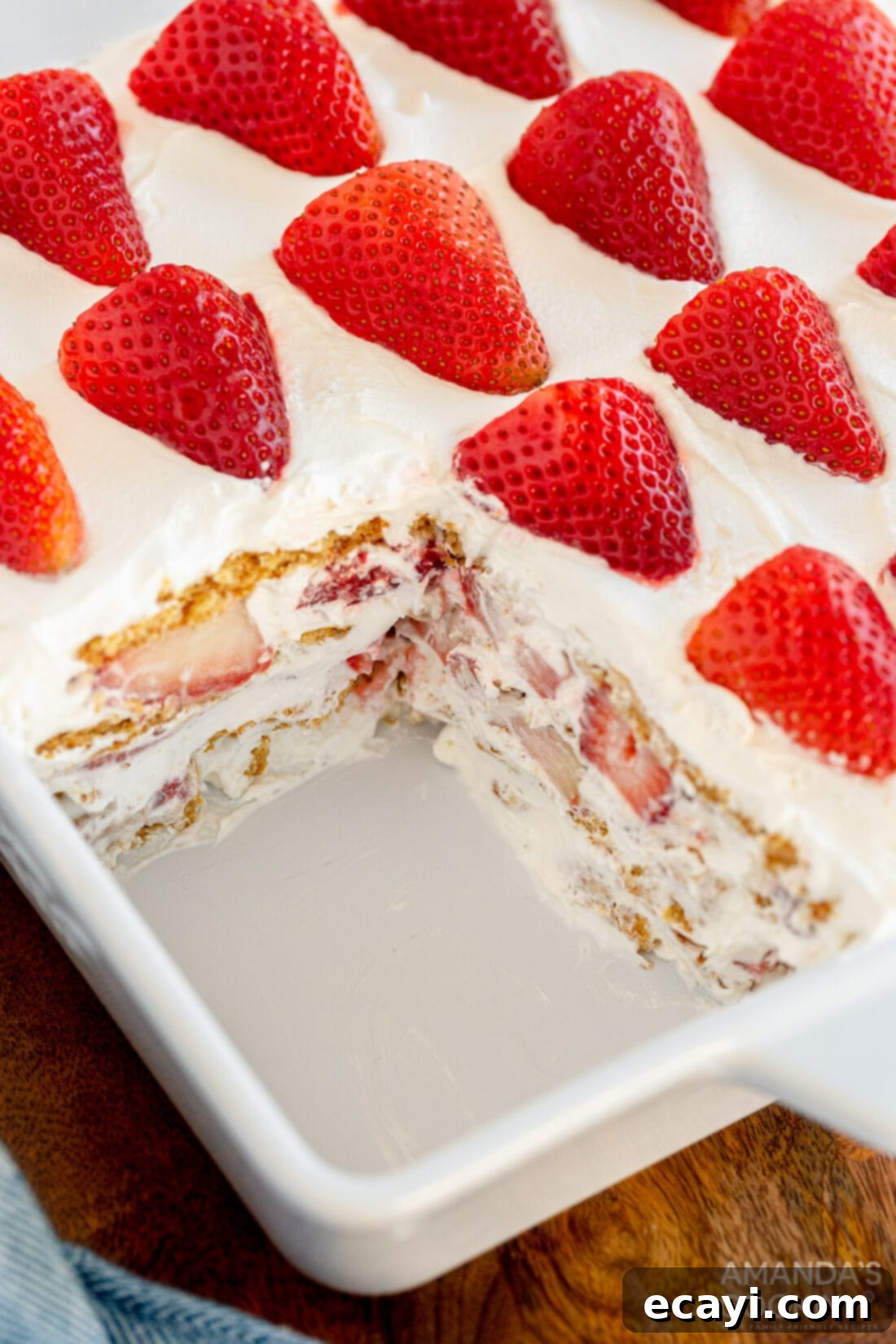 Strawberry Cloud Cake 3 whole strawberry icebox cake with one slice removed, revealing the beautiful layers